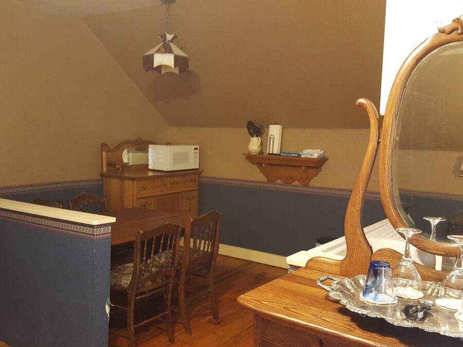 Ein Essbereich mit Holztisch, Stühlen, einem Schrank, einer Mikrowelle und einem Spiegel.