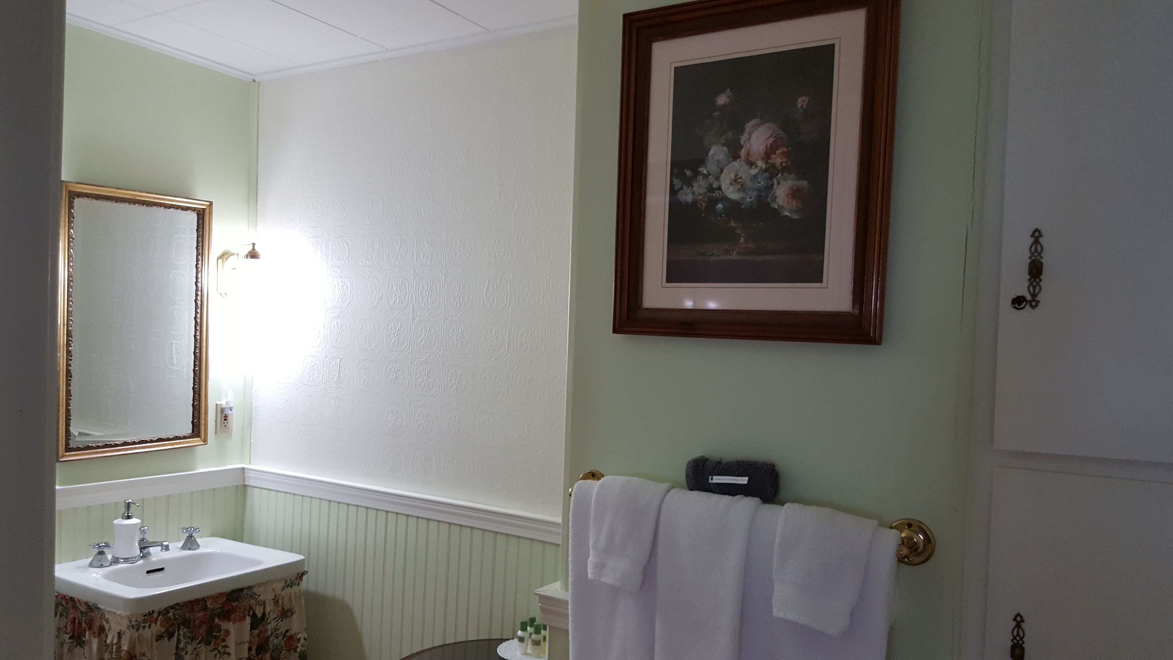 A bathroom with a sink, mirror, and framed floral artwork on the wall.