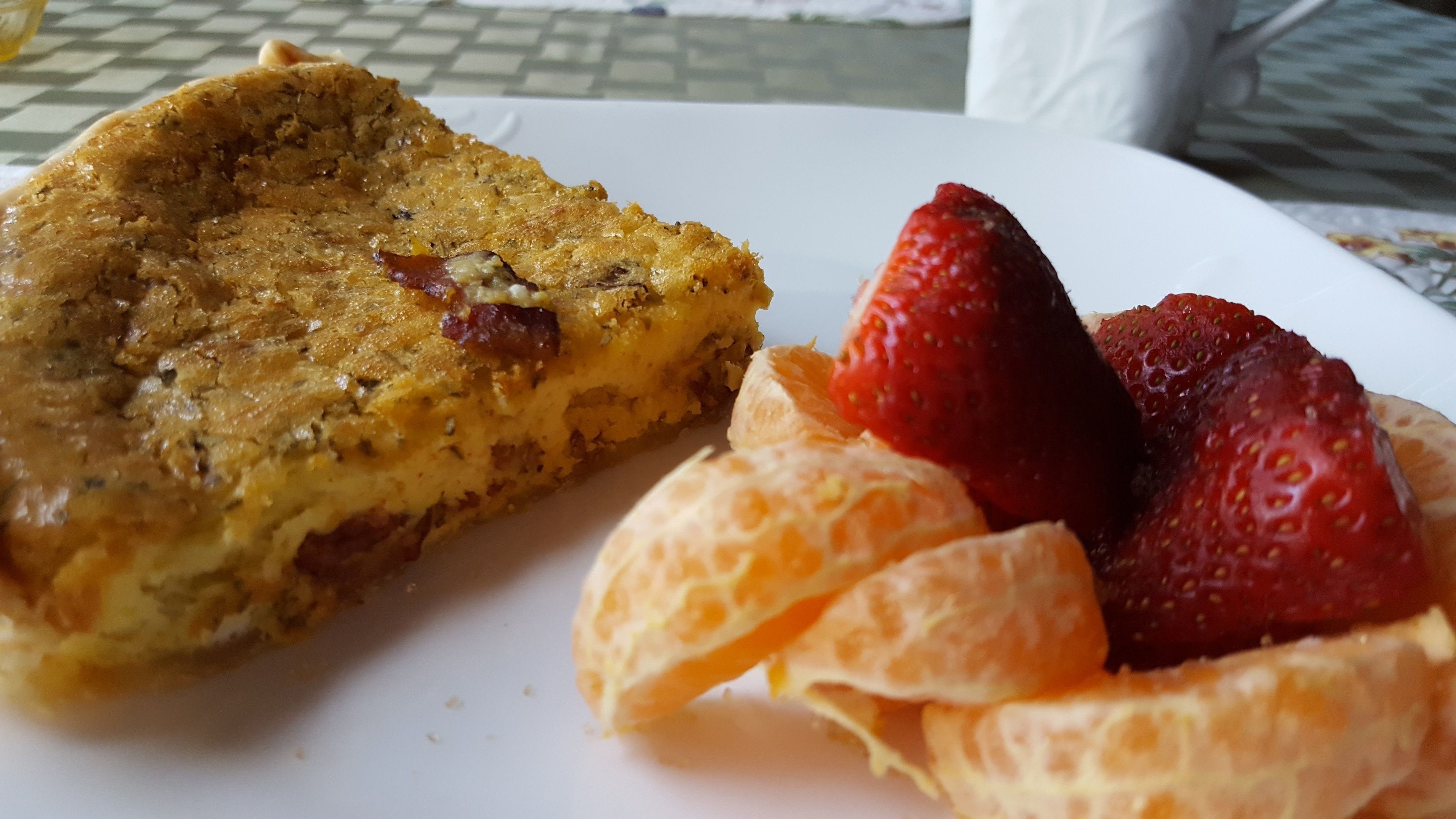Un plato con una porción de quiche y fresas frescas.
