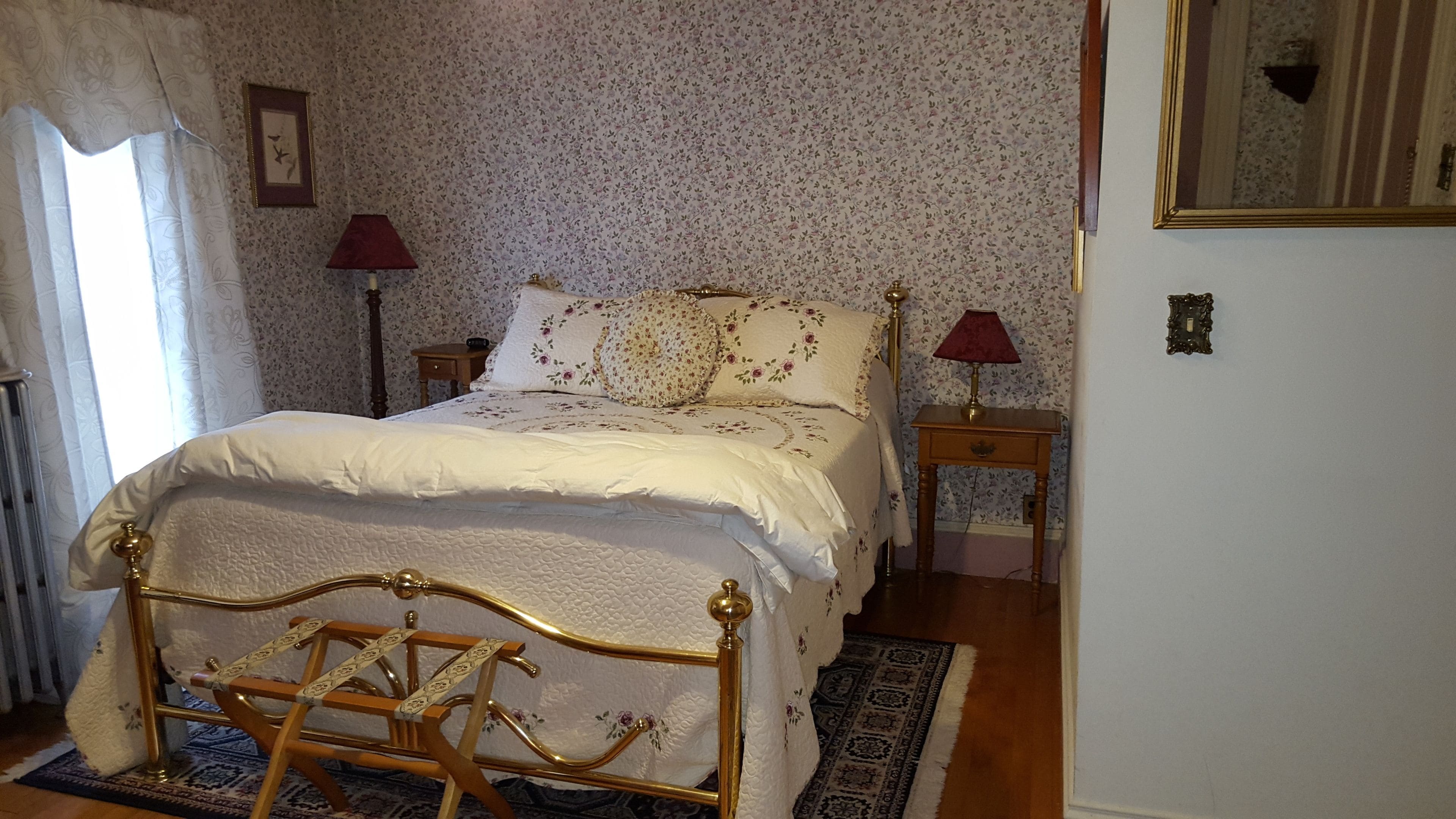 Ein Schlafzimmer mit einem Bett, zwei Nachttischen, einem Heizkörper und einem Fenster mit Vorhängen.