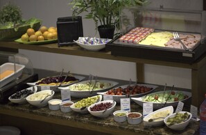 Ein reichhaltiges Buffet mit verschiedenen Speisen, darunter Obst, Gemüse und Fleisch.