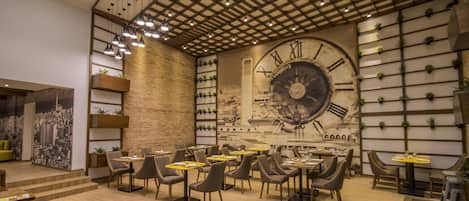 A modern restaurant with a large wall clock, wooden tables, and chairs.