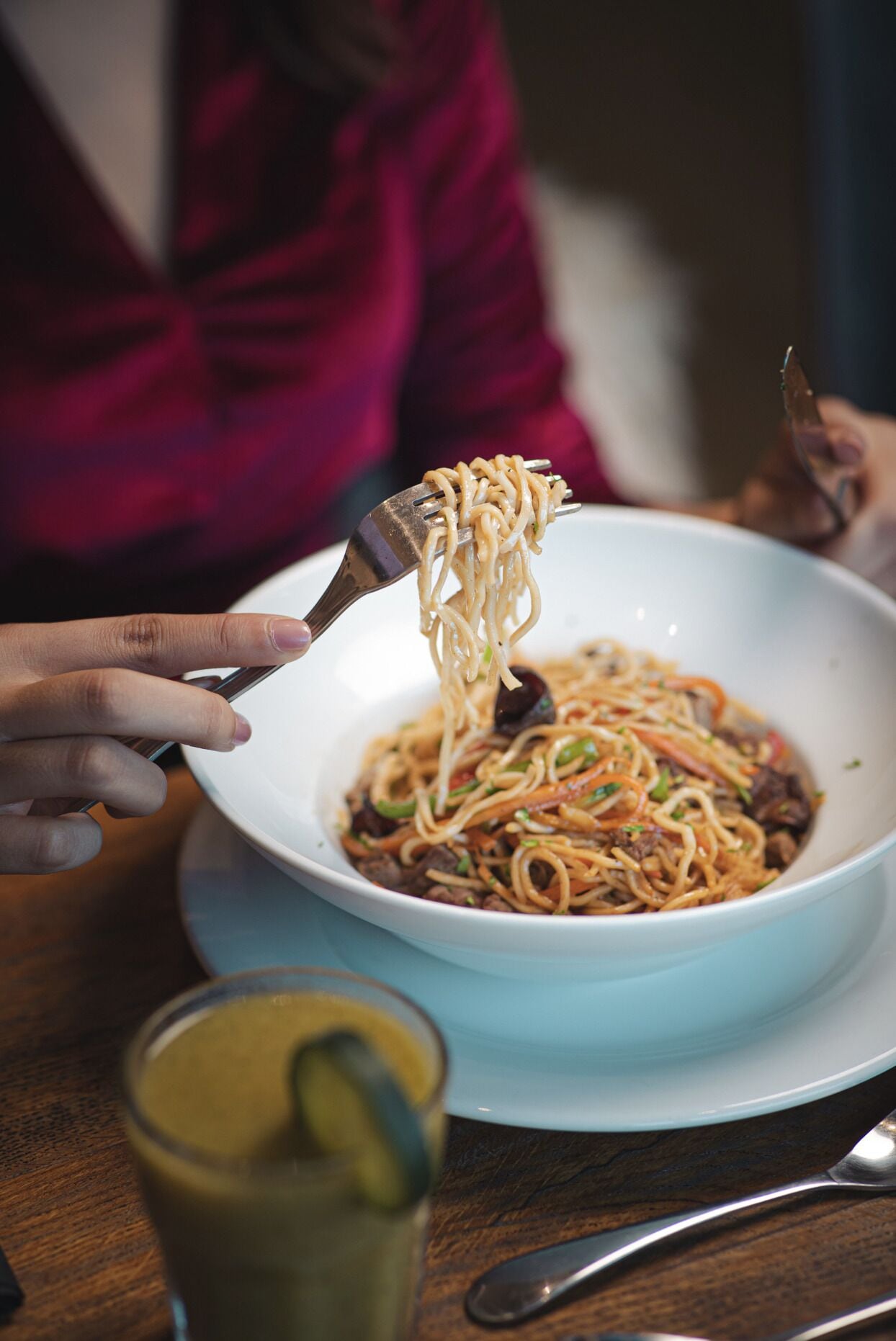 Una ciotola di noodles sollevata con bacchette.