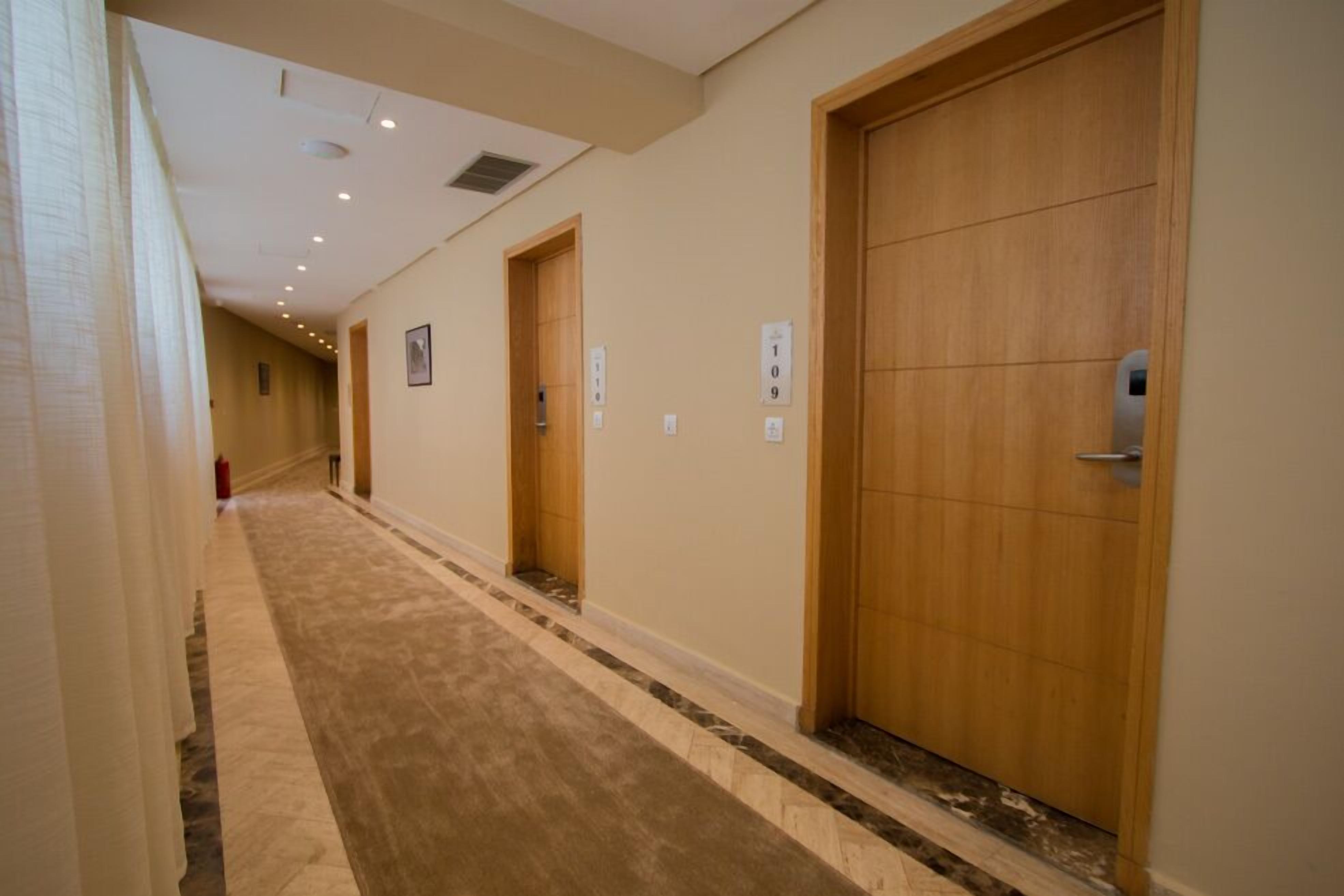 A hallway with wooden doors, numbered signs, and a carpeted floor.