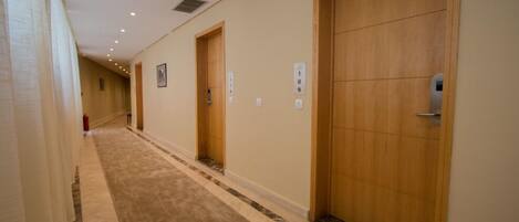 A hallway with wooden doors, numbered signs, and a carpeted floor.