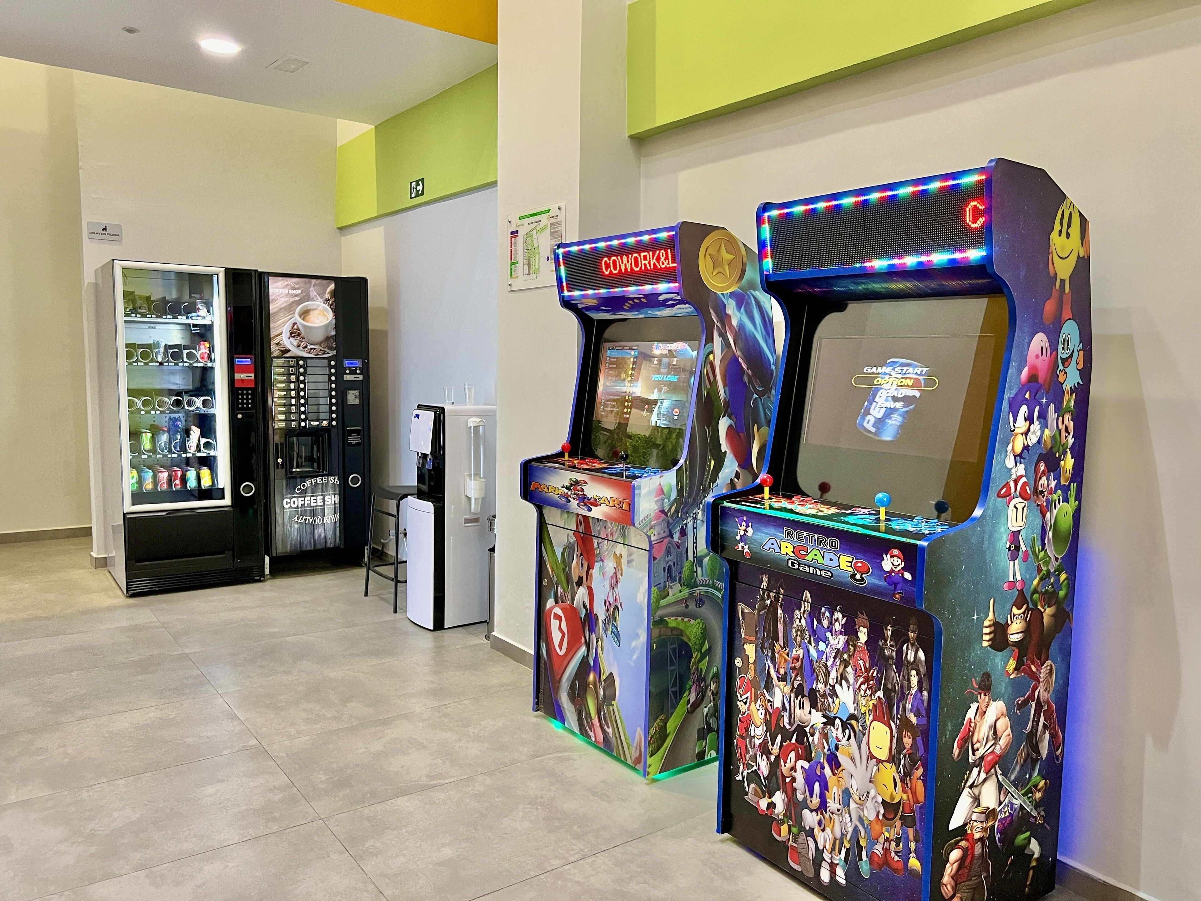 A gaming area with retro arcade machines, a coffee machine, and a vending machine.