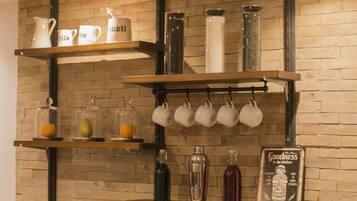 Een keuken met houten planken vol keukengerei, flessen en een bord.