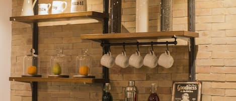 A kitchen with wooden shelves holding kitchenware, bottles, and a sign.