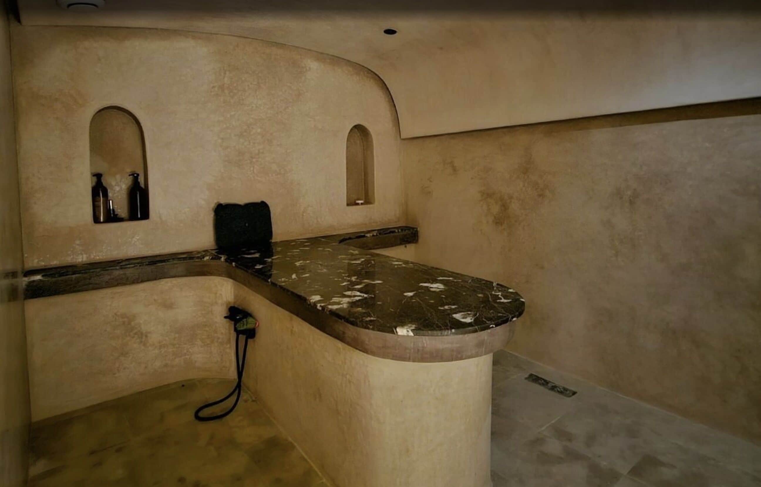 A bathroom with a curved vanity, two small windows, and a shower area.