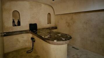A bathroom with a curved vanity, two small windows, and a shower area.