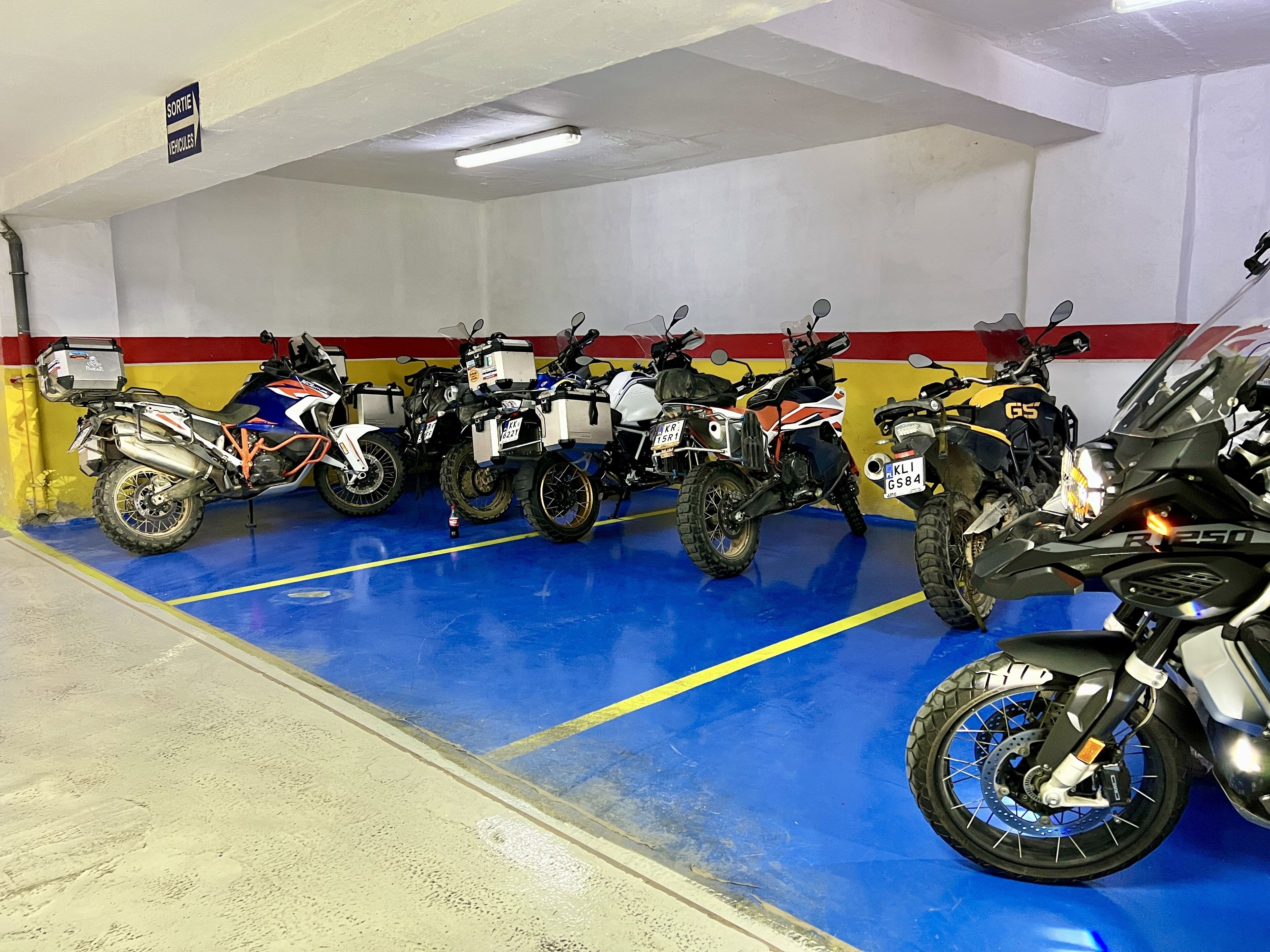 A parking garage with several motorcycles parked in a row.