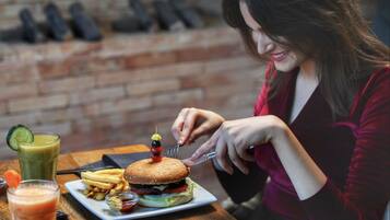 A person dining at a restaurant with a burger, fries, and drinks on the table.