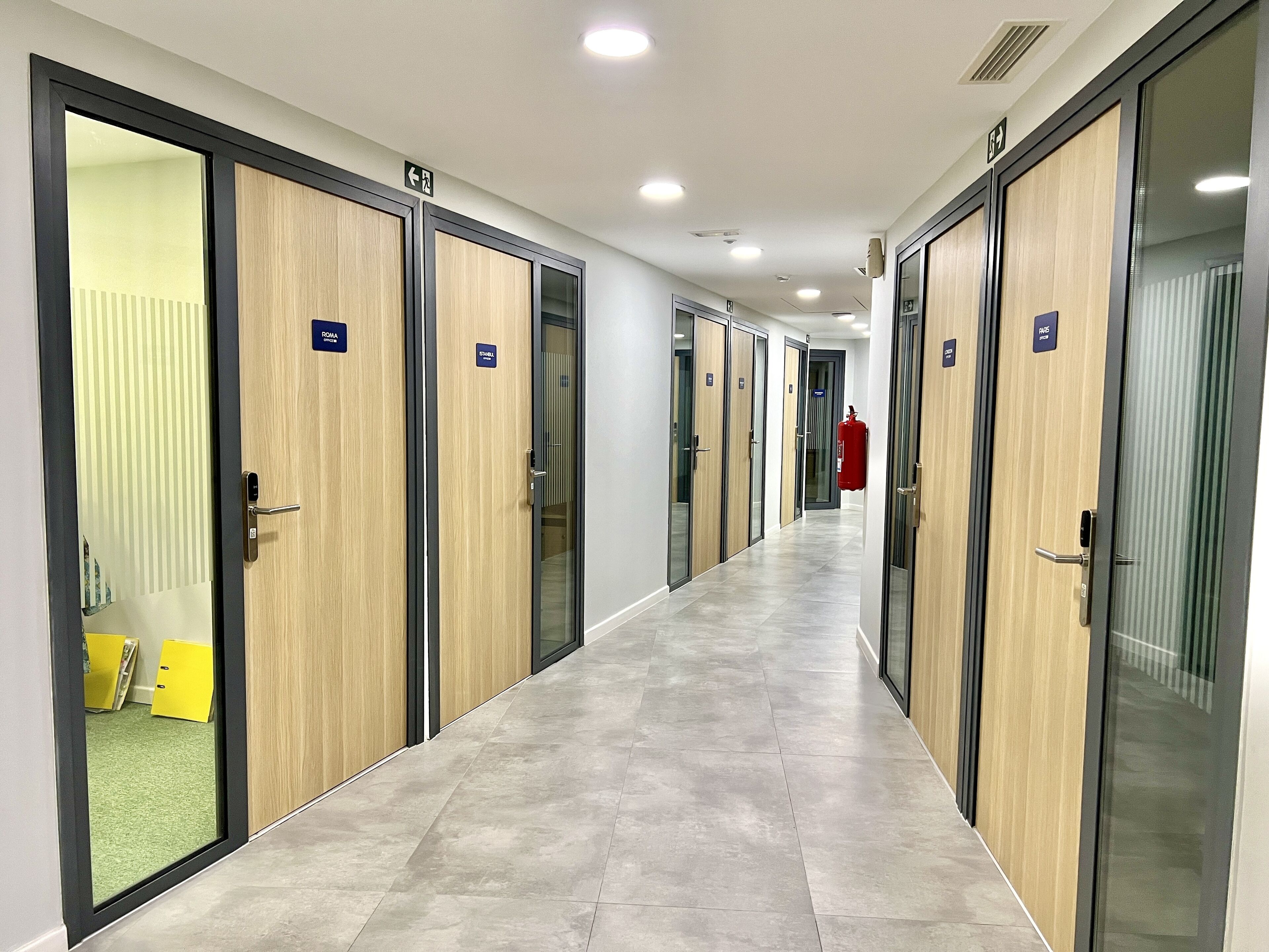 A hallway with multiple doors, each labeled with room names and numbers.