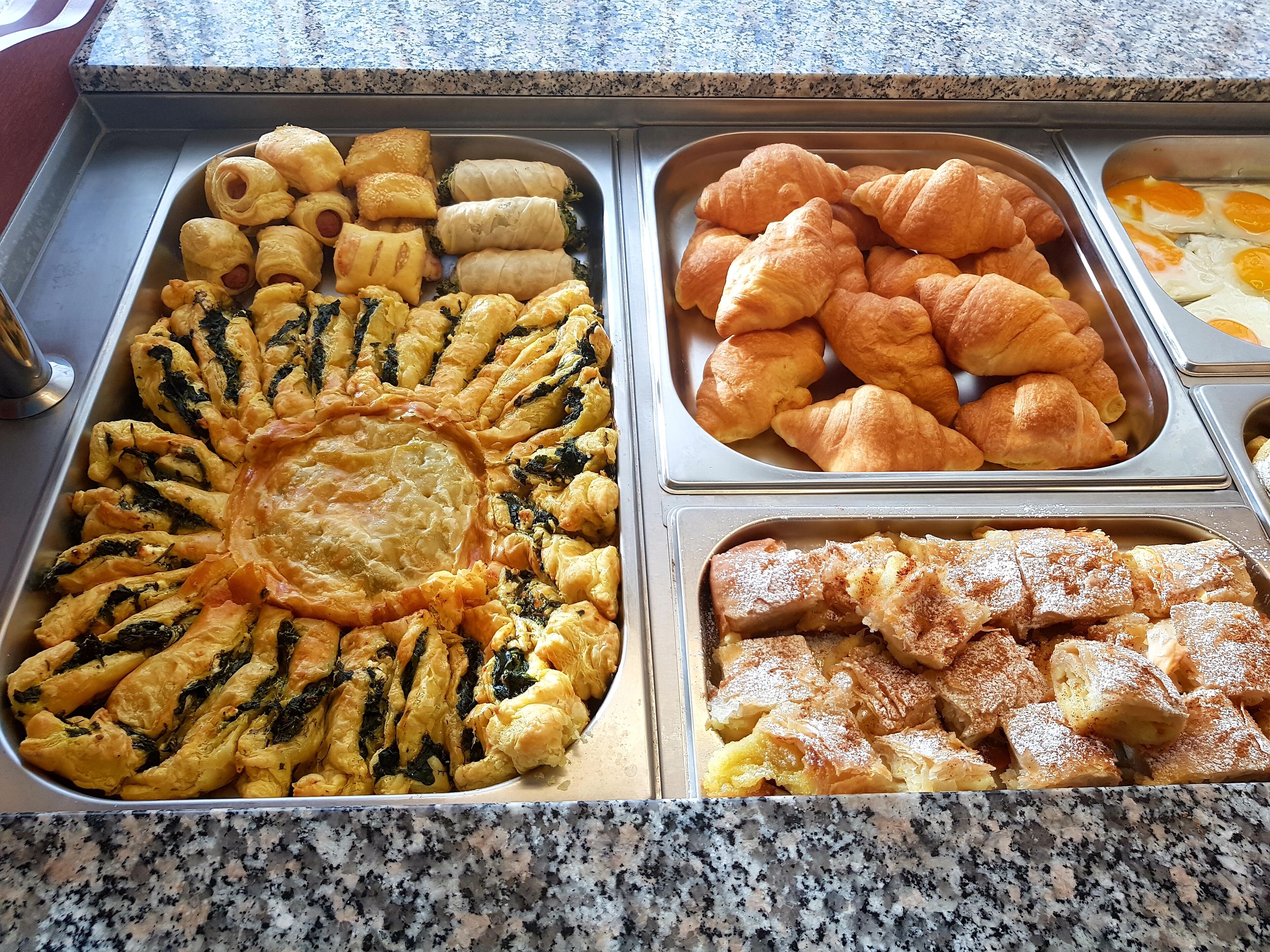 A buffet with various baked goods including pastries, pies, and bread.