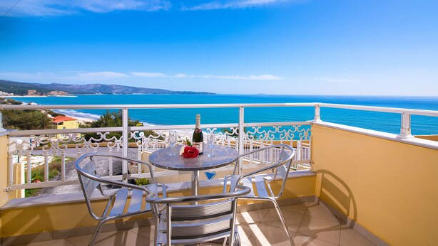 A balcony with a table and chairs, overlooking a coastal view. - Diamond Hotel (Thasos)
