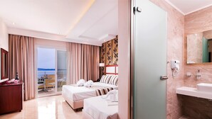 A hotel room with a bed, a desk, a chair, a bathroom with a sink and mirror, and a view of the sea. - Diamond Hotel (Thasos)