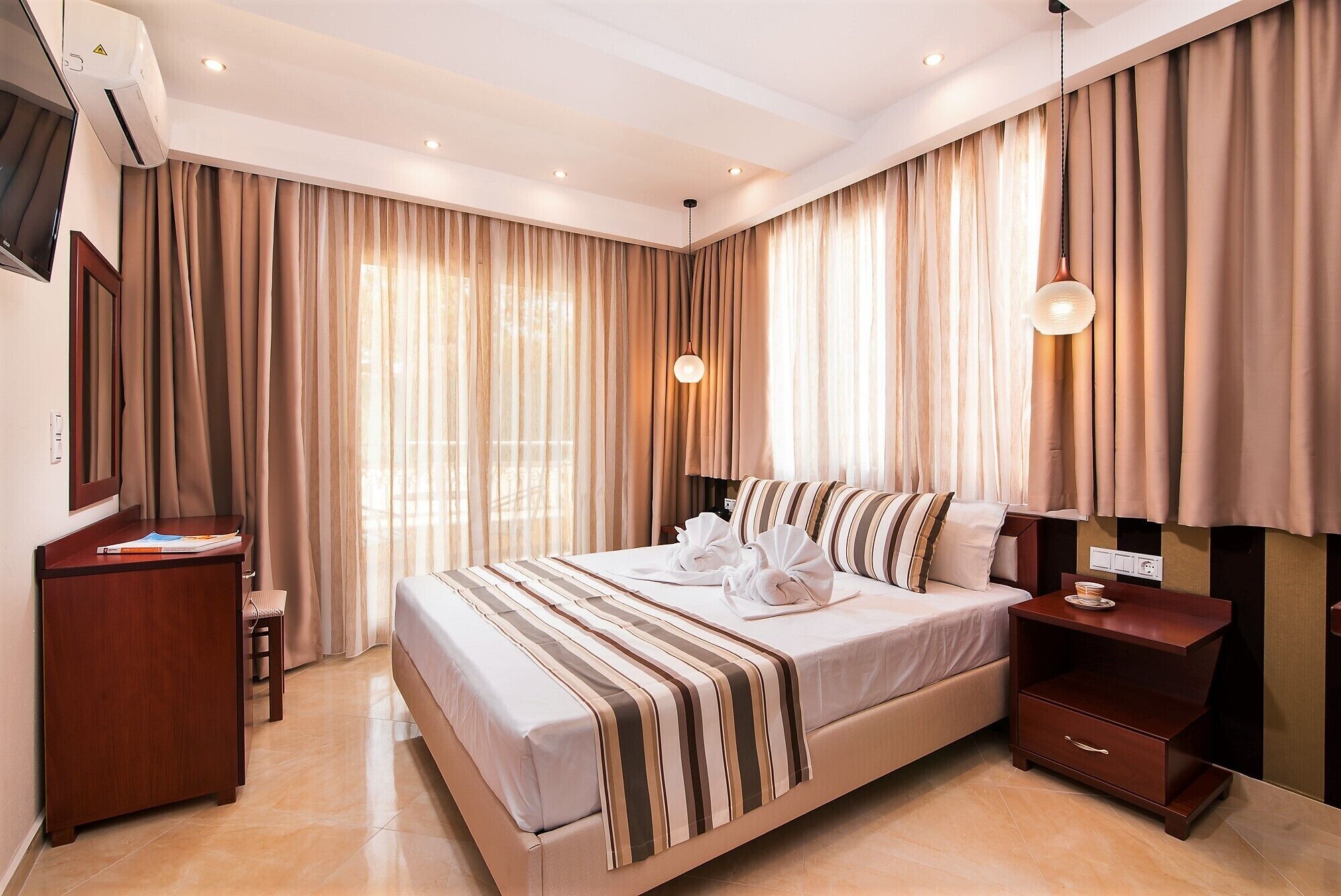 Una habitación de hotel moderna con una cama grande, una mesita de noche, un escritorio y un armario.