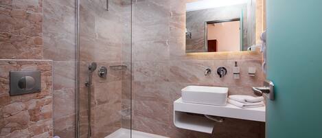 Un bagno moderno con doccia a vetro, lavandino bianco e servizi igienici.