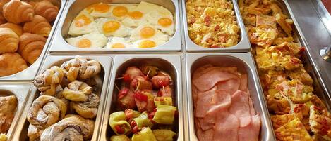 A buffet with various food items including eggs, ham, and pastries.