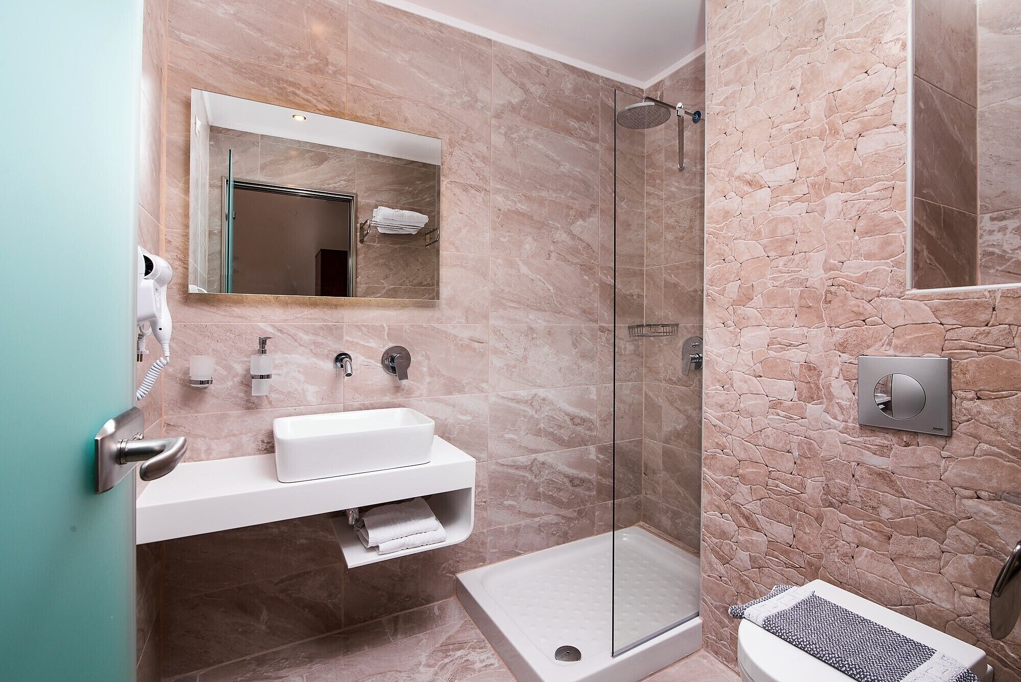 Ein modernes Badezimmer mit einer Glaskabine zur Dusche, einem weißen Waschbecken und einem Handtuchhalter.