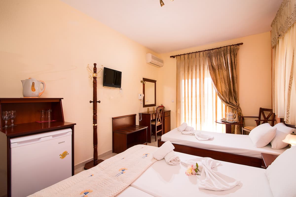 A hotel room with two beds, a desk, a chair, a television, and a minibar.