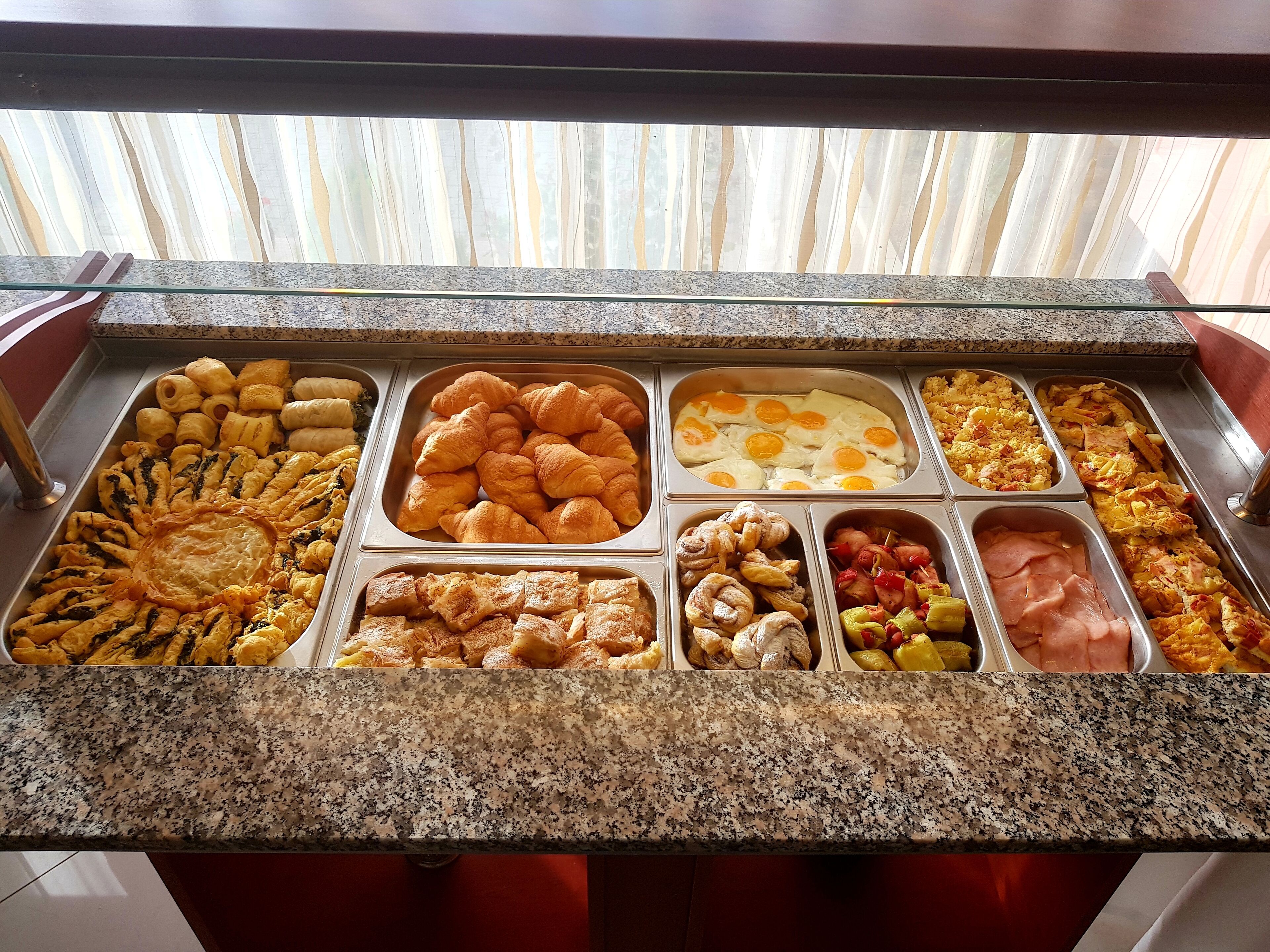 Een buffet met diverse gerechtjes, waaronder gebak, eieren en vlees.