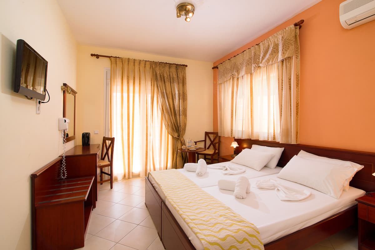 A hotel room with a bed, a desk, a chair, a TV, and curtains.