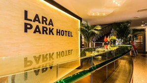 Señal del Hotel Lara Park con barandilla de cristal y palmeras al fondo.