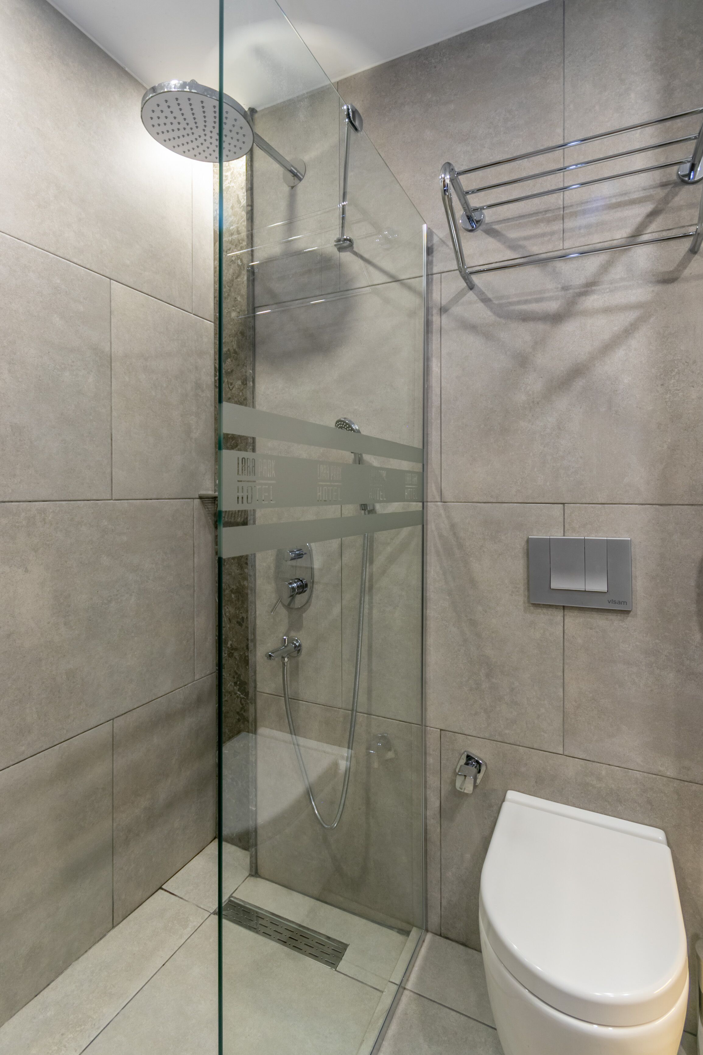 Une salle de bain moderne avec une douche à parois de verre, des toilettes et un porte-serviettes.