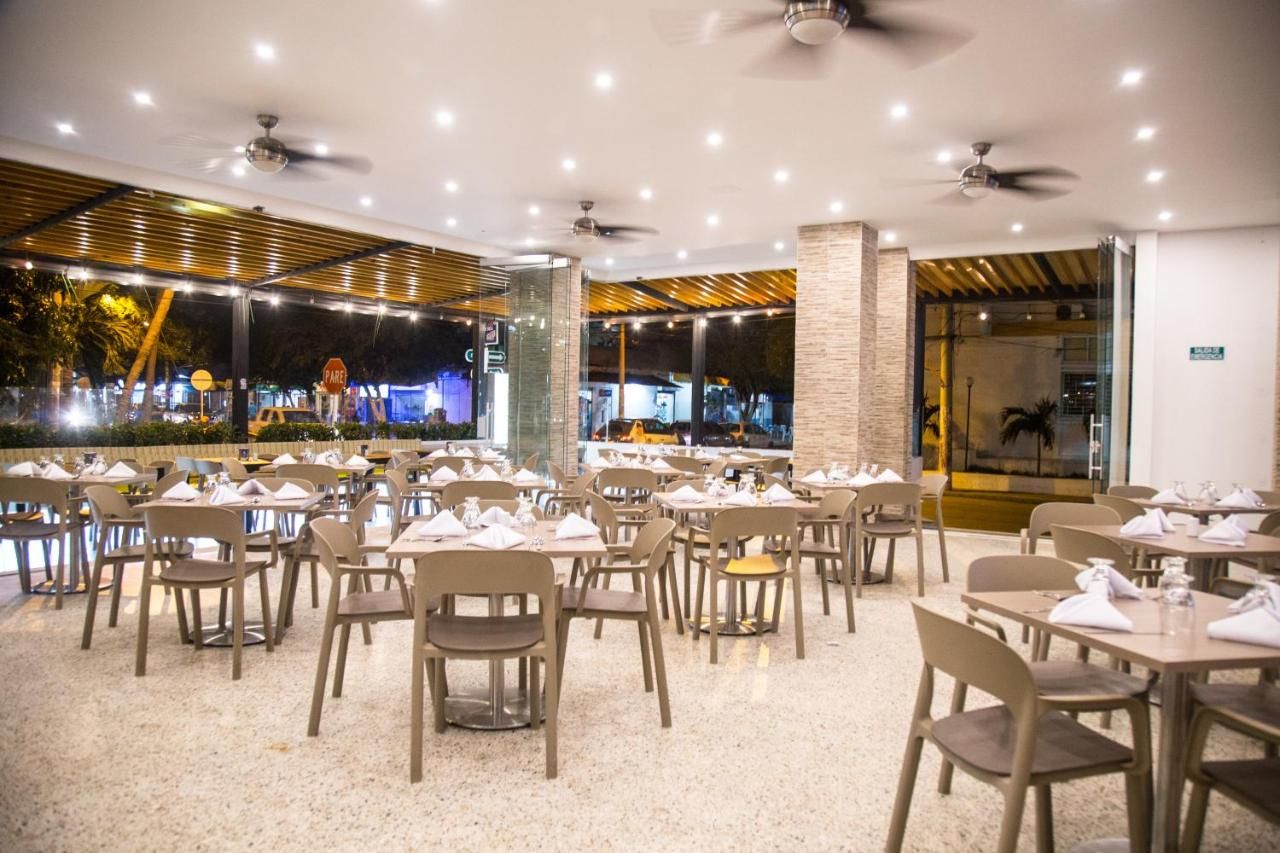 Un restaurante con varias mesas y sillas, ventiladores de techo y vistas al exterior.