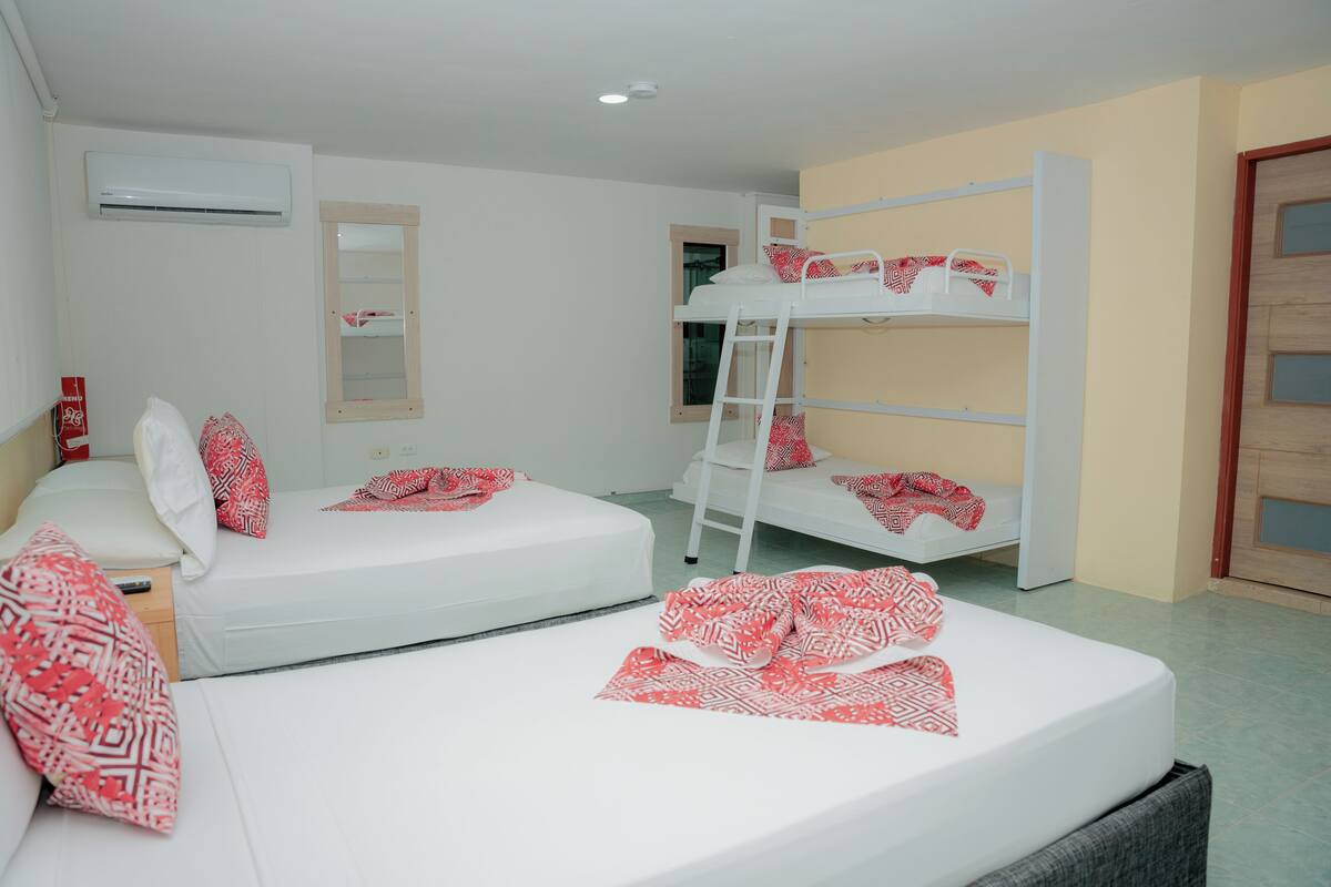 Una habitación con dos camas individuales, una litera, una escalera, un espejo y un equipo de aire acondicionado.