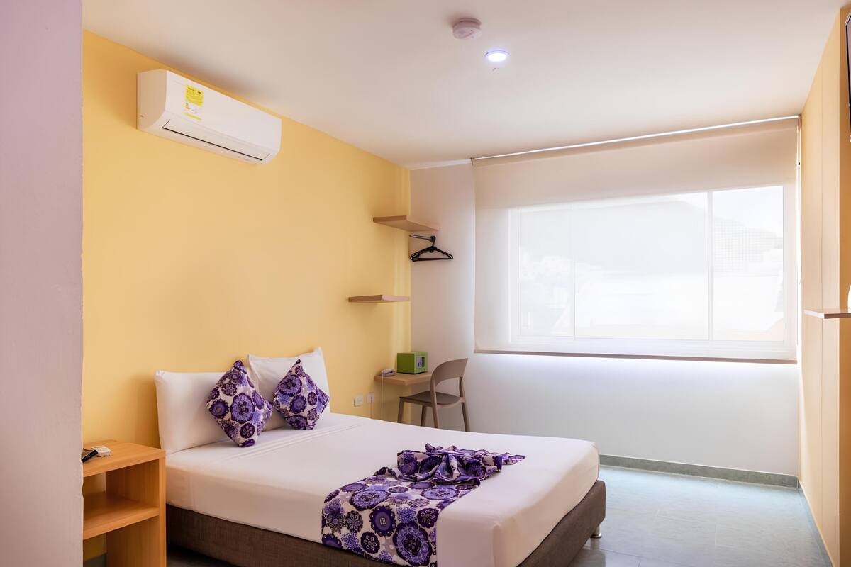 Habitación de hotel con cama, escritorio, silla y ventana con vistas.