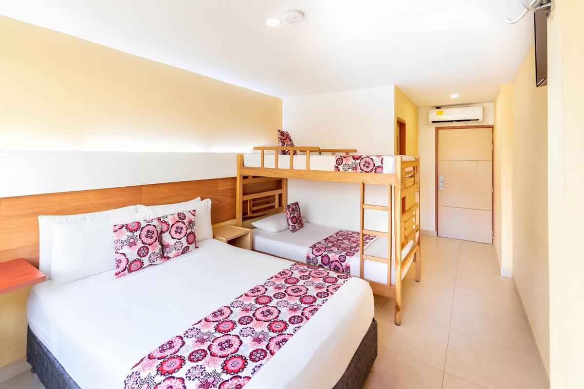 Una habitación de hotel con una cama litera, una cama individual y una escalera de madera.