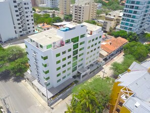 A multi-story building with a flat roof, surrounded by greenery and other buildings. - Hotel Portobahia (Santa Marta)