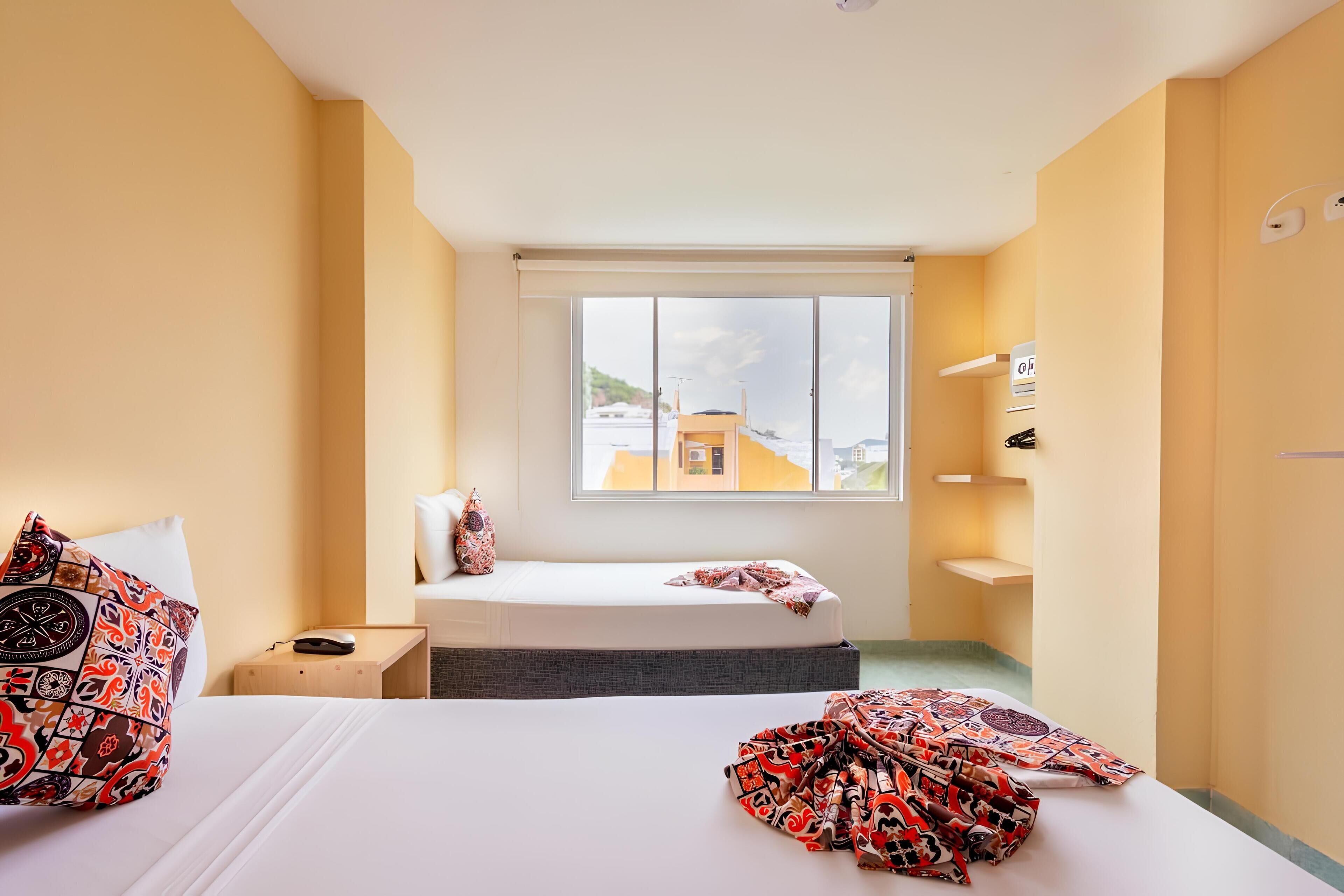 Una habitación de hotel con cama, mesita de noche y ventana con vista a la ciudad.