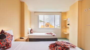 Una habitación de hotel con cama, mesita de noche y ventana con vista a la ciudad.