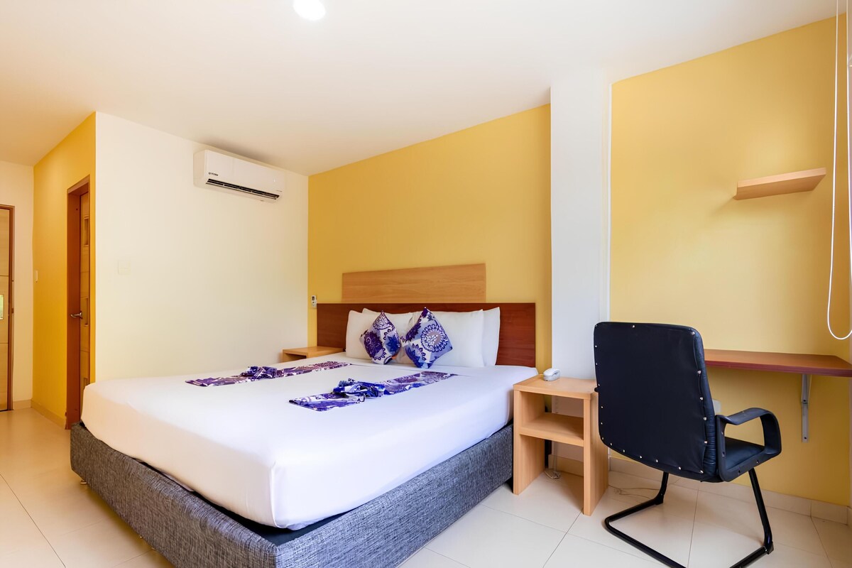 A hotel room with a bed, a desk, and a chair.