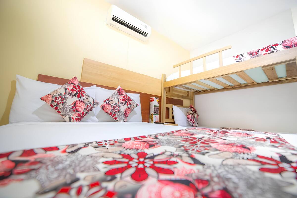 Una cama litera con estructura de madera, colchón blanco y manta de estampado floral.