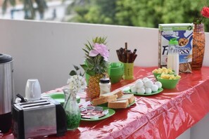 A table with food items, a toaster, a pineapple, a vase with flowers, and a carton of Nestlé Fitness milk. - Emotion Tulum Hotel (Tulum)