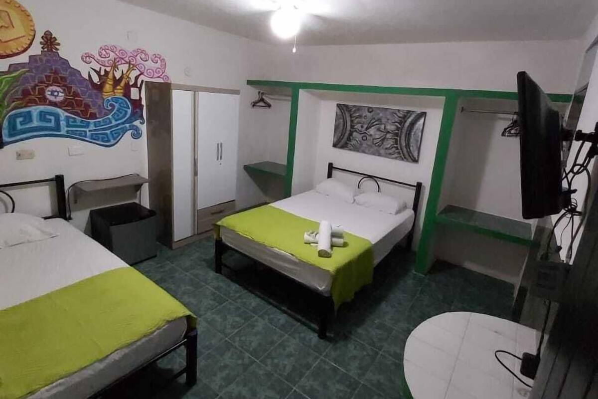A hotel room with two beds, a small desk, a chair, a TV, and a bathroom.