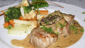 A plate of food with a piece of meat, vegetables, and a creamy sauce. - Hotel-Restaurant SchöpPerle (Häusern)
