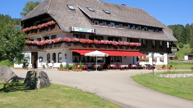 A traditional building with a sloped roof, multiple windows, and a red awning. - Hotel-Restaurant SchöpPerle (Häusern)