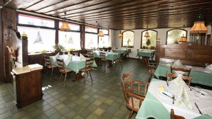 A restaurant with wooden beams, green tablecloths, and wooden chairs. - Hotel-Restaurant SchöpPerle (Häusern)