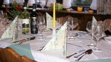 A dining table set with wine glasses, cutlery, and a candle.