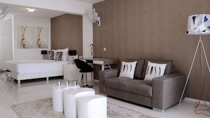 A modern bedroom with a bed, a desk, a sofa, and a standing lamp.