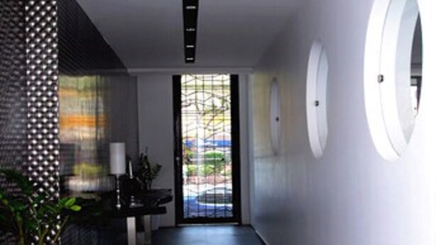A modern hallway with a black and white color scheme, featuring a potted plant, a reception desk, and circular wall decorations.