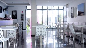 A modern restaurant with a bright interior, large windows, and contemporary furniture.