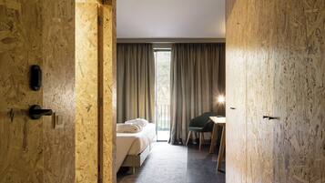Una habitación de hotel moderna con detalles de madera, una cama, un escritorio y vistas al exterior a través de amplios ventanales.