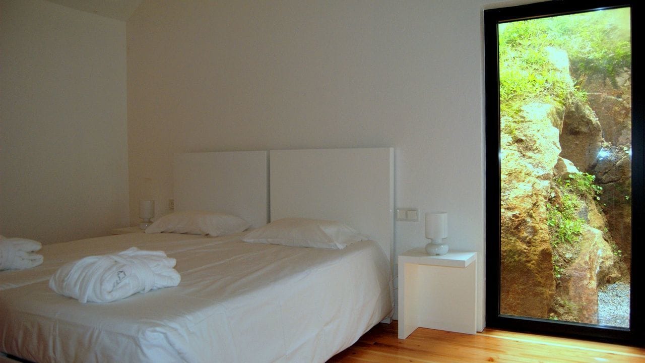 Une chambre à coucher avec un grand lit, une table de chevet et une fenêtre donnant sur un paysage rocheux.