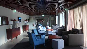 A modern hotel lobby with a wooden ceiling, comfortable seating areas, and large windows.